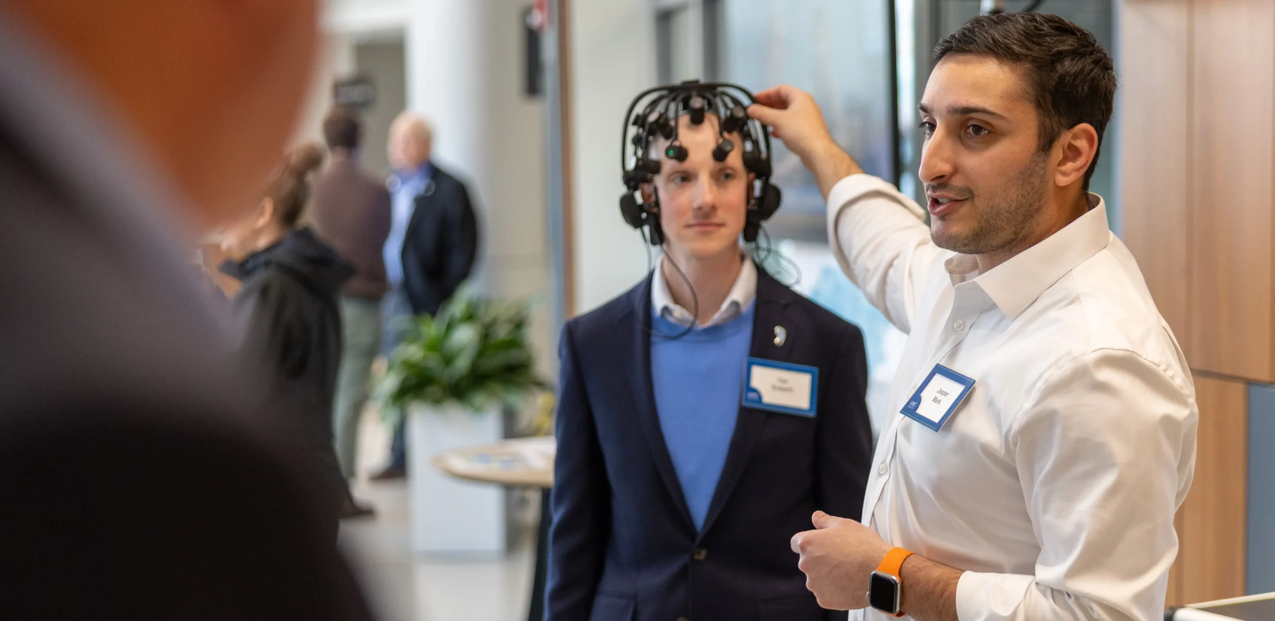 Researcher demonstrating a wearable brain-monitoring cap during a neuroscience research event, showcasing innovative brain-computer interface technology and collaborative medical research.