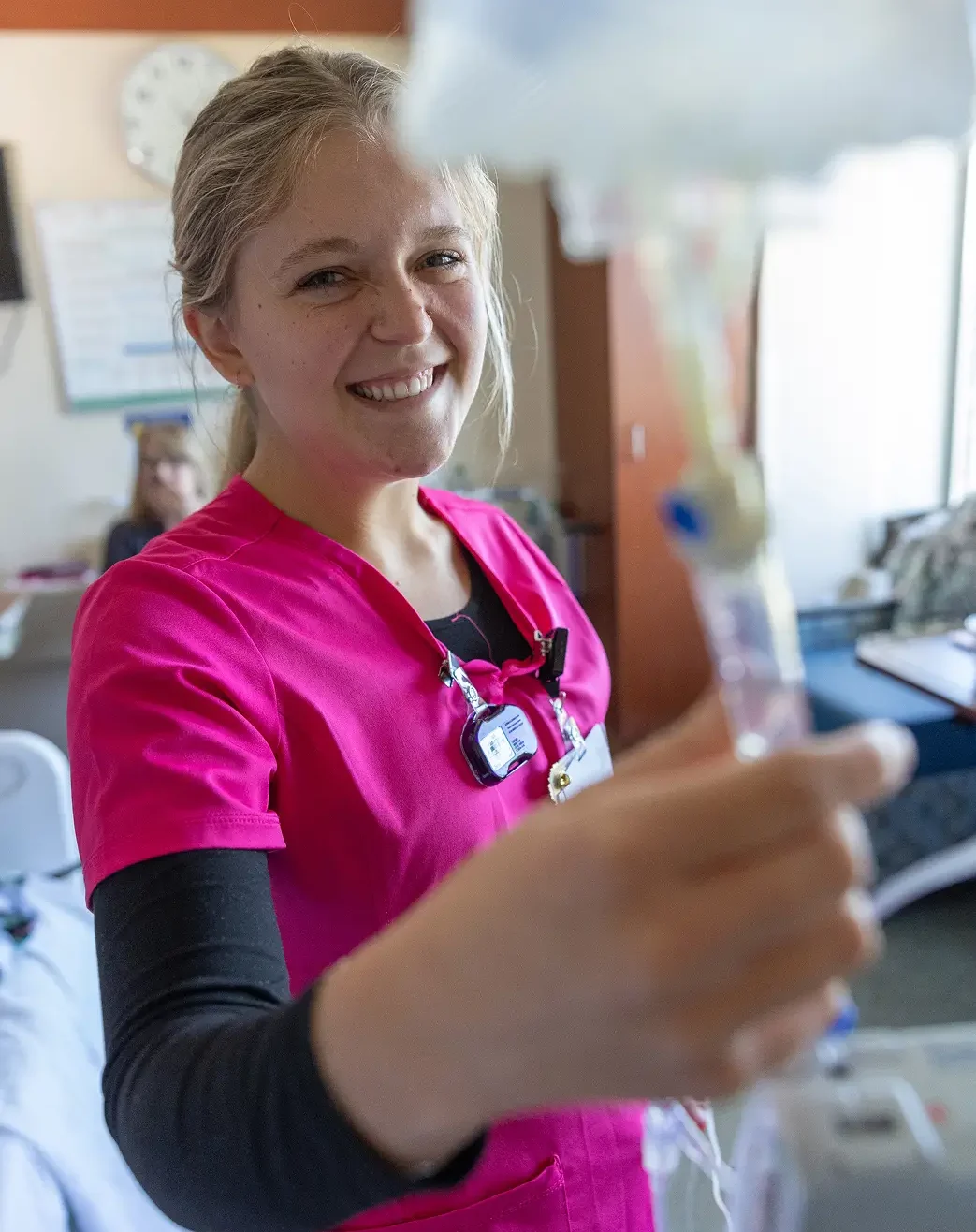 Healthcare nurse in pink scrubs uses the latest genetic research to provide specialized clinical care.