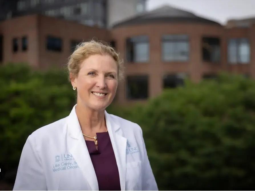 Medical oncologist standing outside a cancer center, representing leadership in clinical trials, cancer research, and patient-centered oncology care.