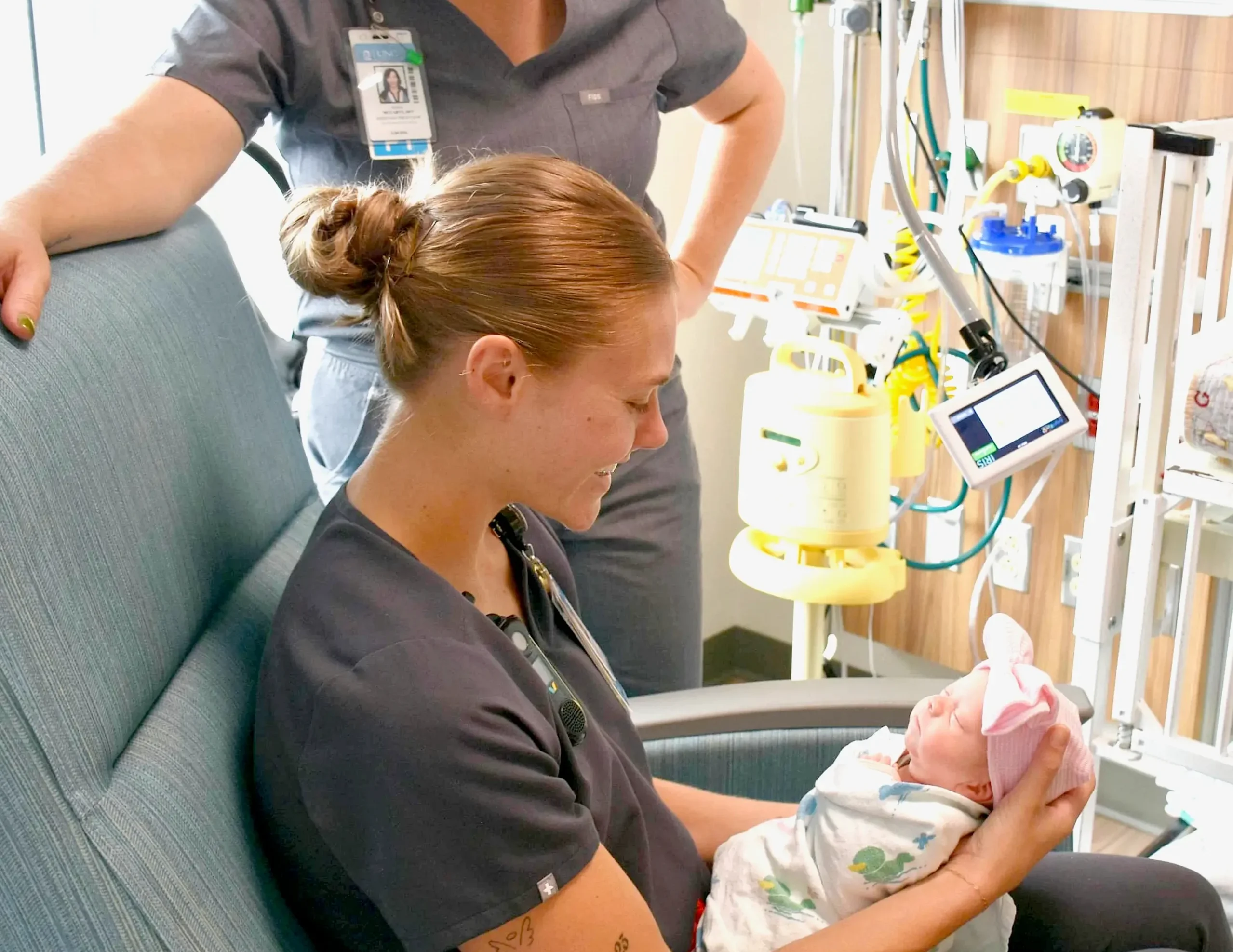 Two UNC Health clinicians care for a newborn baby in a hospital room, putting childhood disease research to work for compassionate support during the infant’s early care.