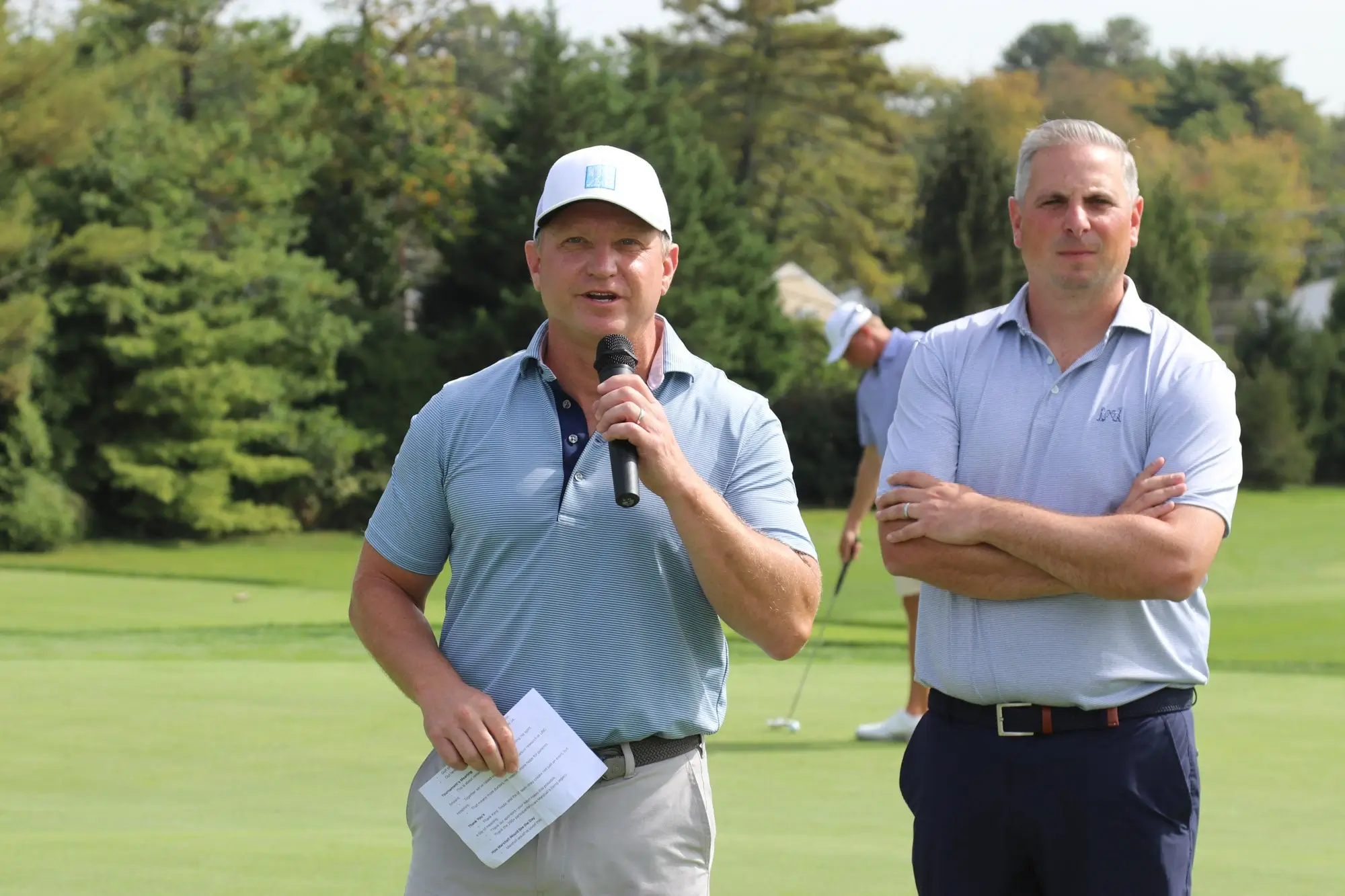Two golfers address fundraiser attendees at a charity event for cancer research