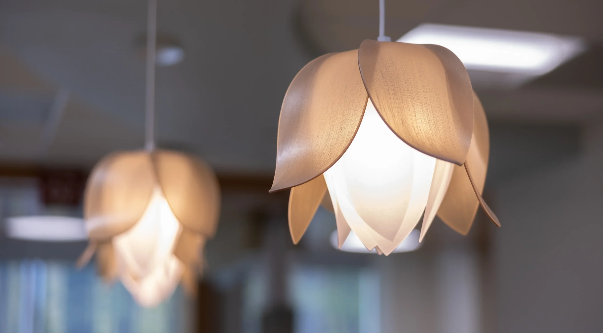 Warm pendant lights with flower-shaped wooden shades hanging in a softly lit patient memorial.