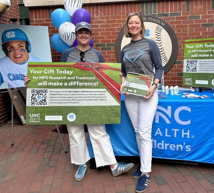 Volunteers promote UNC Children’s MPS research and treatment at a community event outside a baseball stadium.