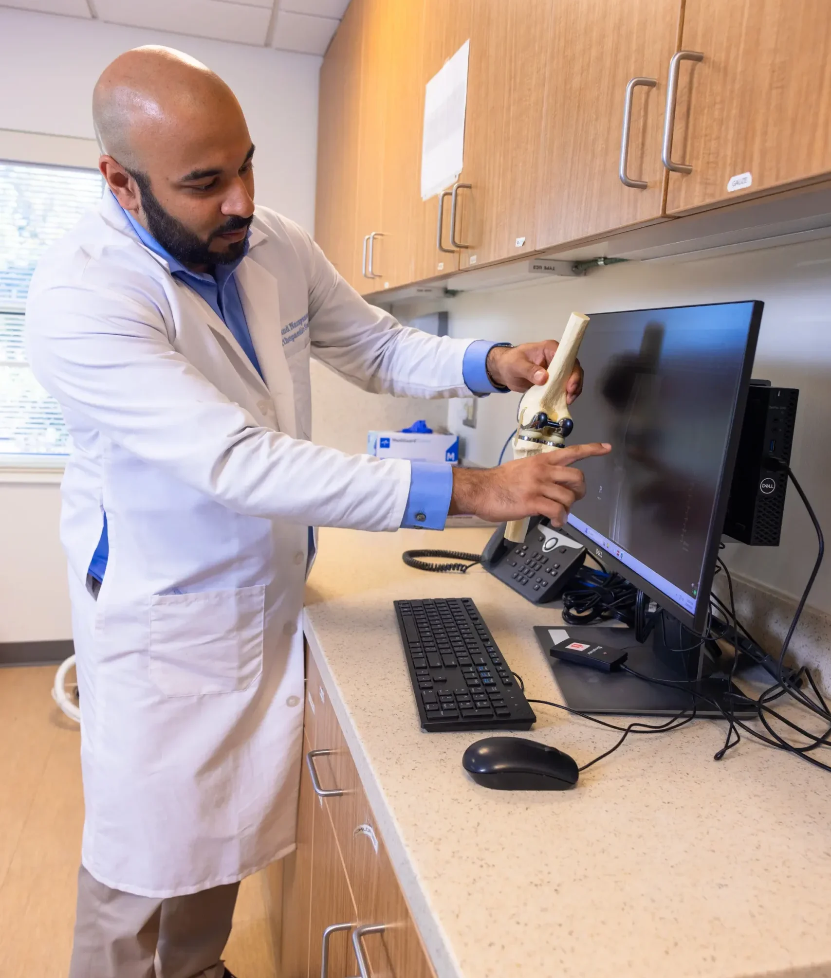 Orthopedic physician demonstrating a knee joint replacement model developed through UNC research.