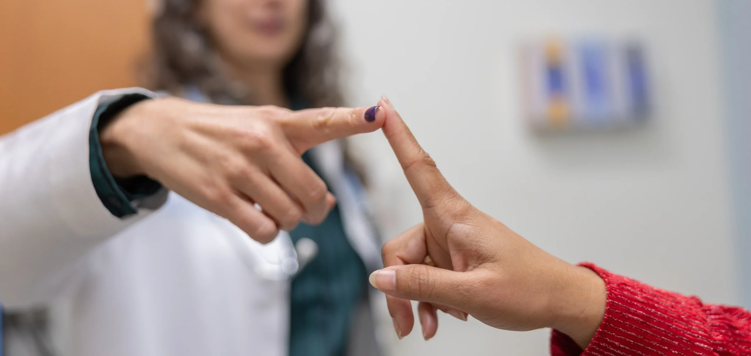 Healthcare professional and patient gently touching fingertips during a patient care interaction made possible by planned giving