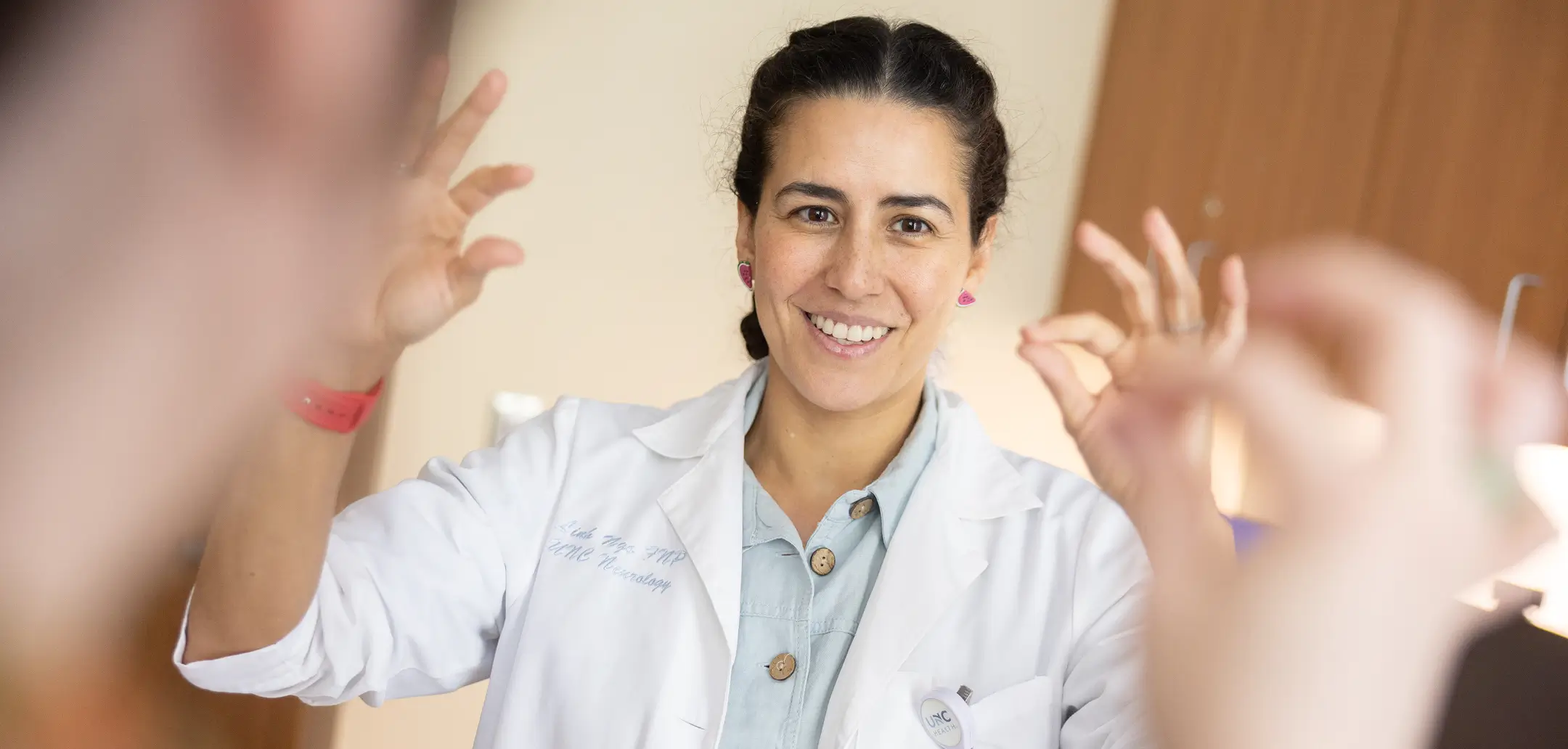 Neuroscience researcher performs a neurological examination on a patient, demonstrating hand coordination and motor function assessment during a clinical visit.