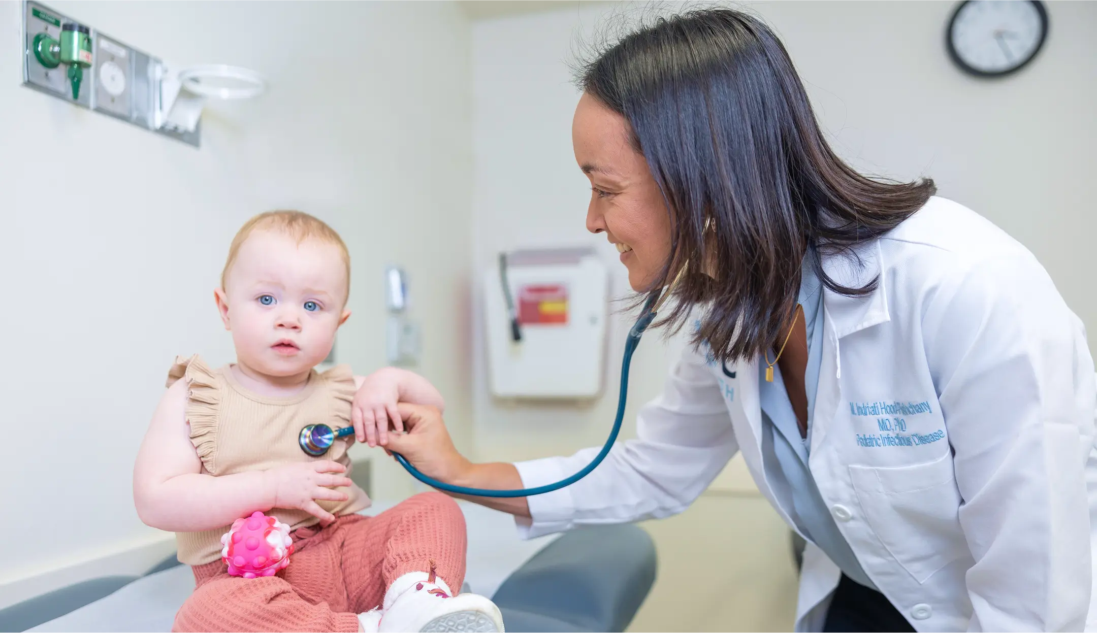 UNC pediatrician using a stethoscope to examine a baby during a routine wellness checkup in a medical examination room supported by UNC Health Foundation