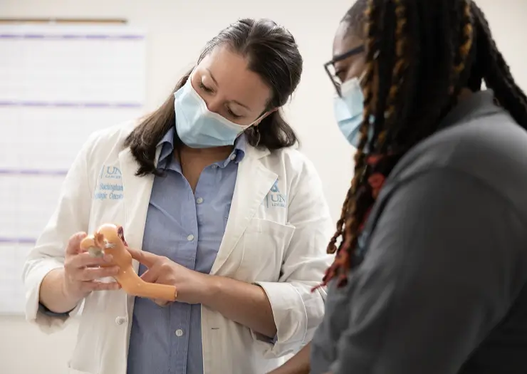 Orthopedic specialist and UNC Health using a knee joint model to explain anatomy and treatment options during a patient consultation.