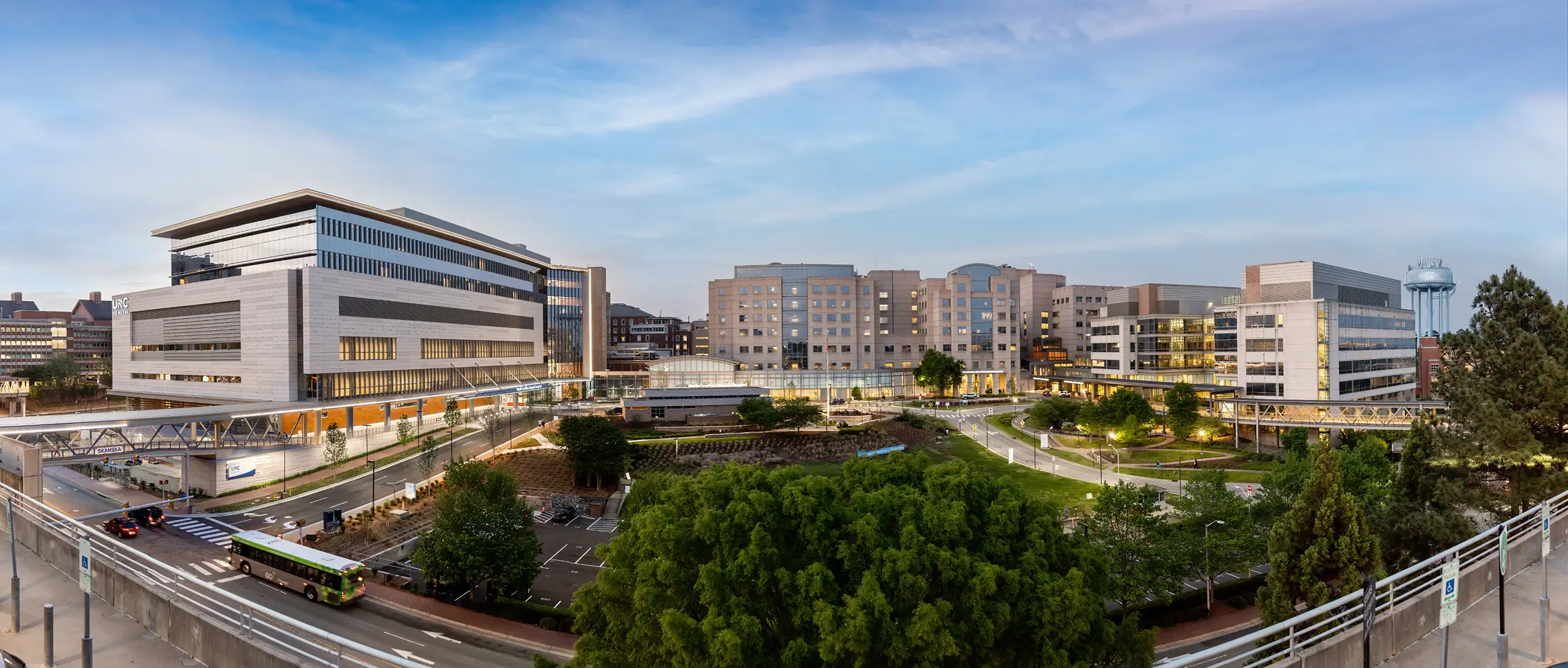 Panoramic view of the UNC Health medical center campus with hospital buildings, landscaped grounds, roads, and pedestrian walkways.