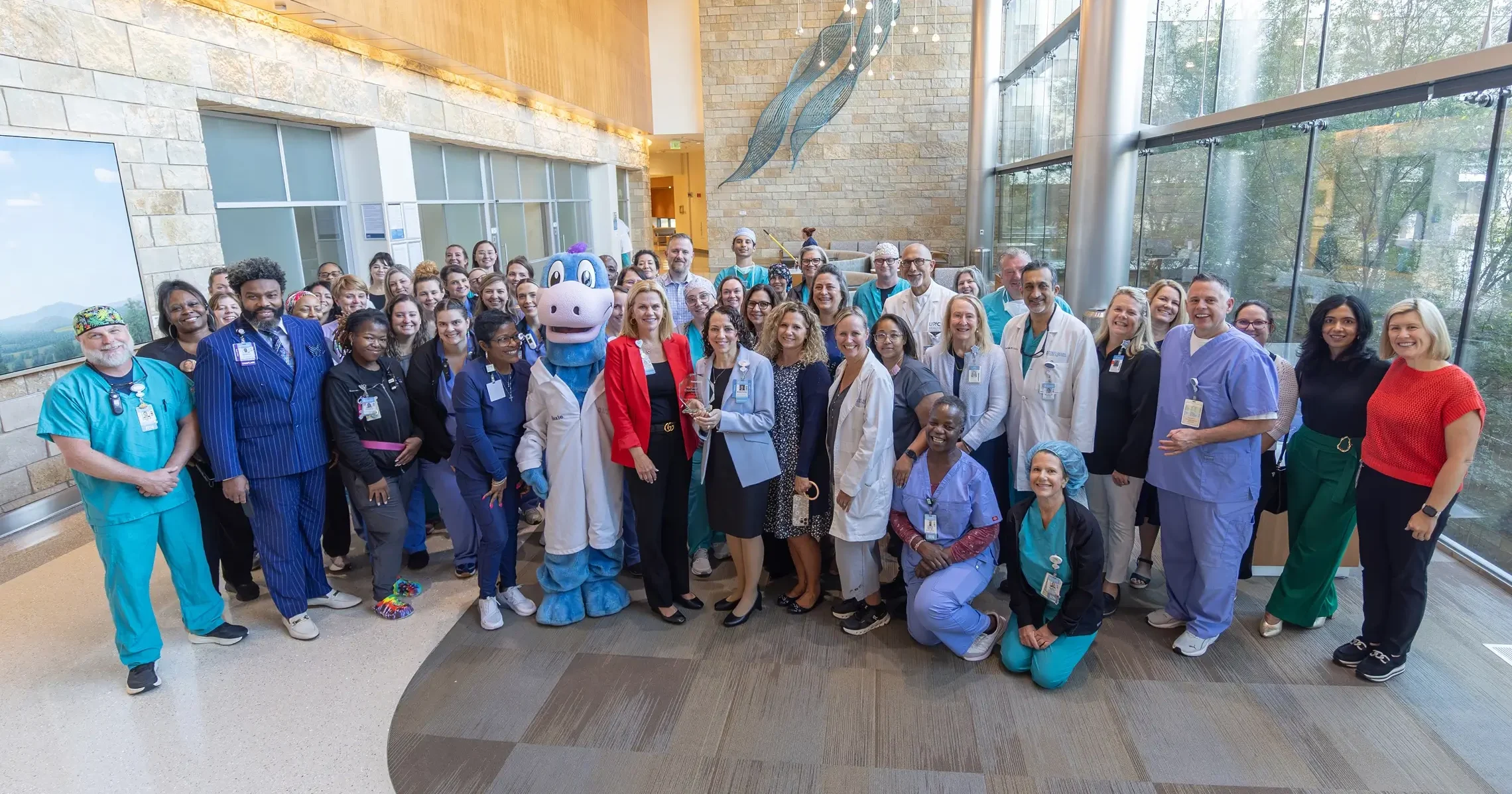 Large group of UNC Health healthcare professionals gathered together in a hospital atrium.