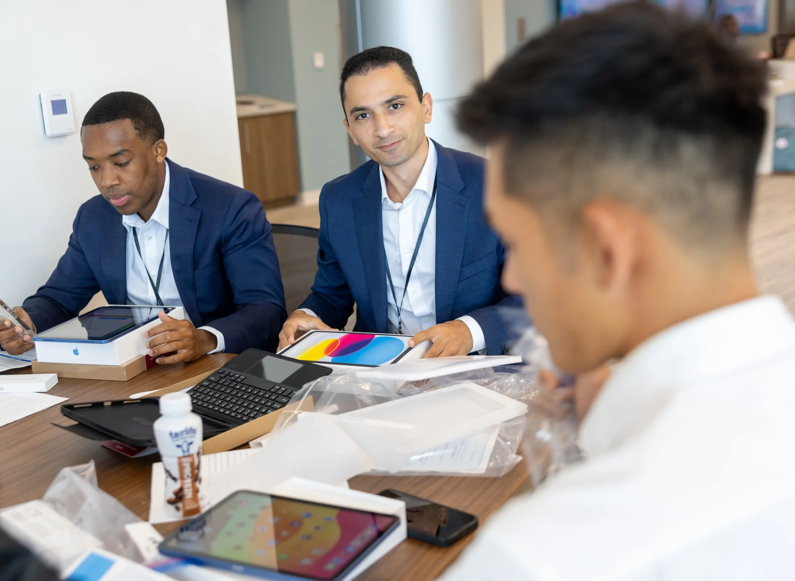 Healthcare professionals gathered around a table using tablets and discussing materials during a meeting.