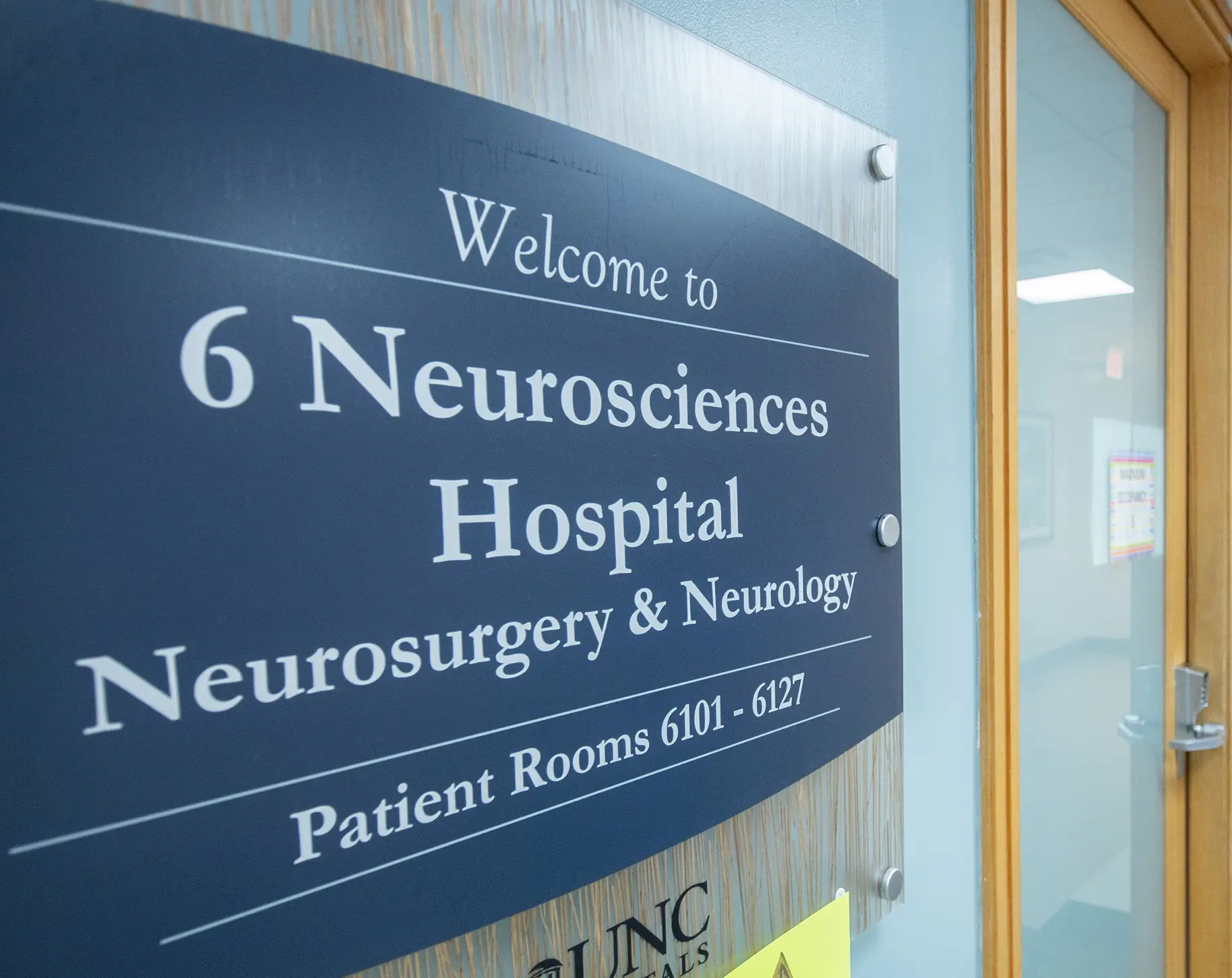 Welcome sign for 6 Neurosciences Hospital and Neurology patient rooms in a hospital hallway.