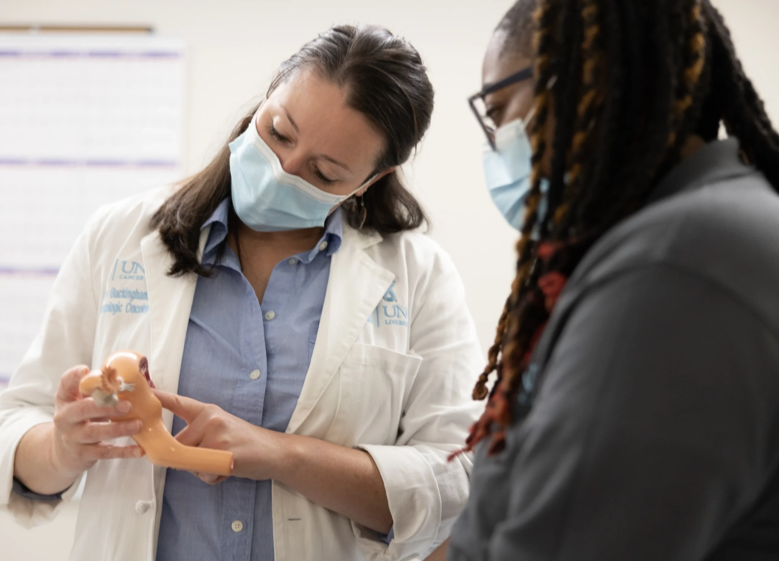 A UNC Health gynecologic oncology physician uses an anatomical model to explain advances in women's health research during a clinical visit