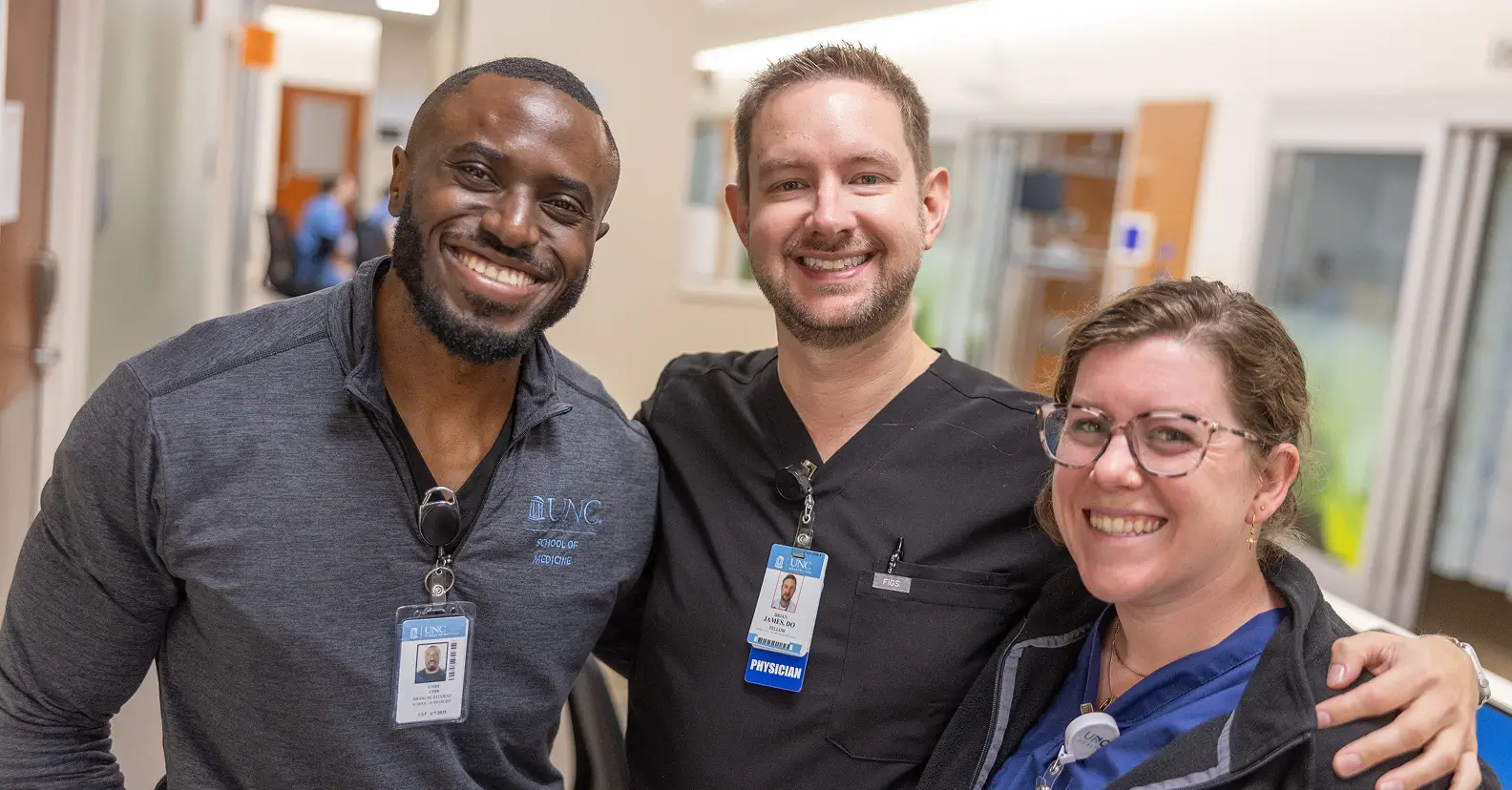 Three healthcare professionals smiling together in a hospital corridor, highlighting how healthcare philanthropy makes real impacts in medicine.