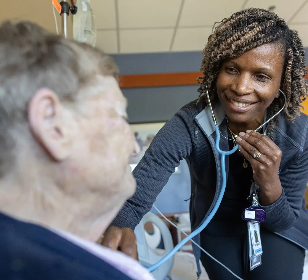Compassionate nurse using a stethoscope while caring for an elderly patient from rural NC as part of a program funded by cancer research donors
