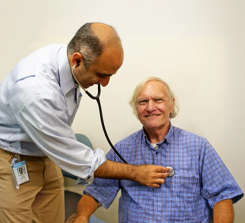 Physician using a stethoscope to perform a routine health examination on an older adult patient as part of a program made possible by foundation grants