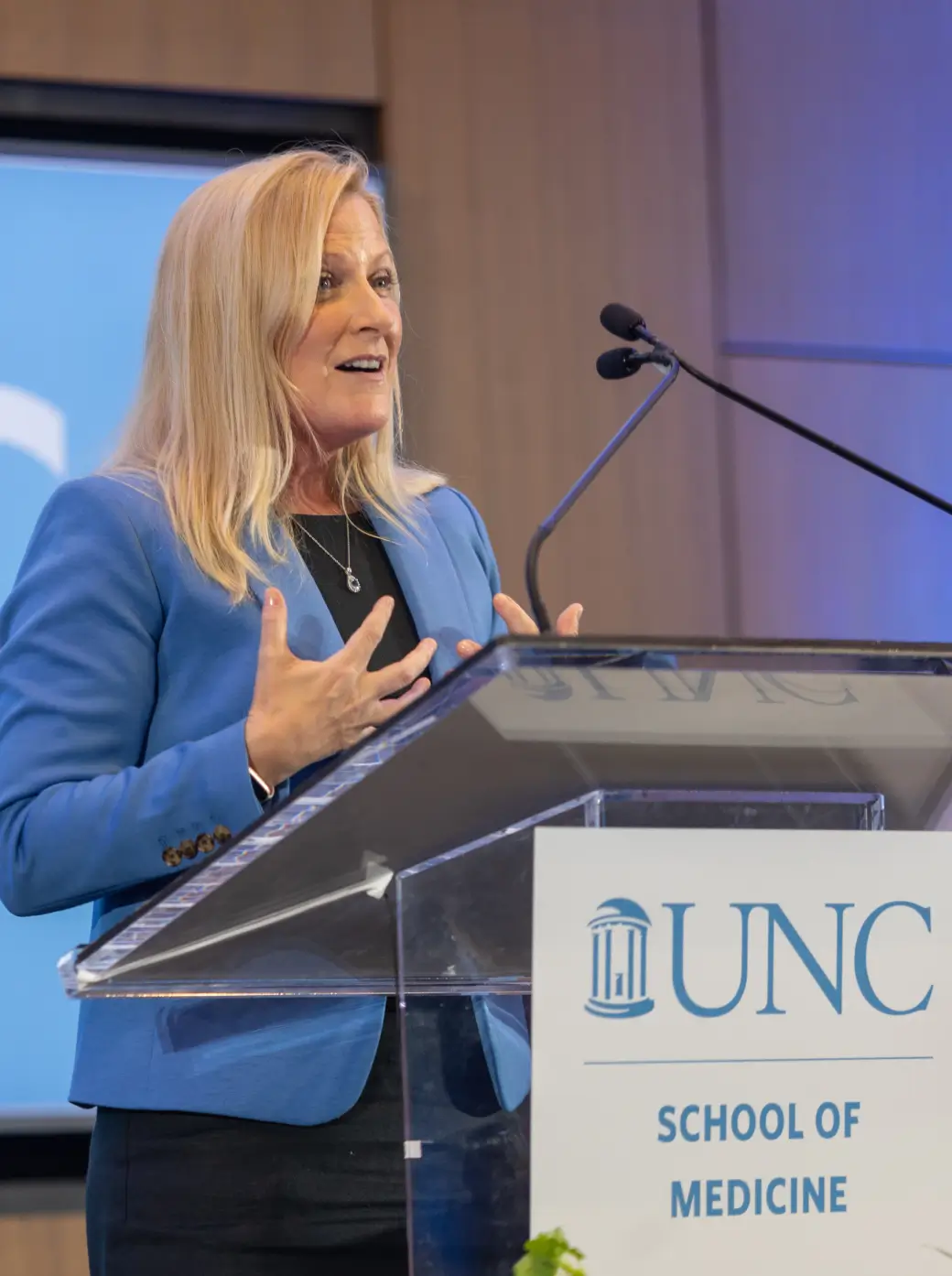 Healthcare leader delivering a keynote presentation at a medical conference from a podium at a school of medicine event for UNC Health Foundation.