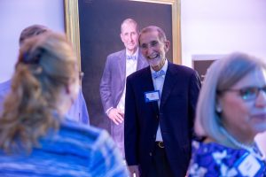 Bill Roper, MD, stands near his portrait at the event to officially open Roper Hall at UNC School of Medicine.