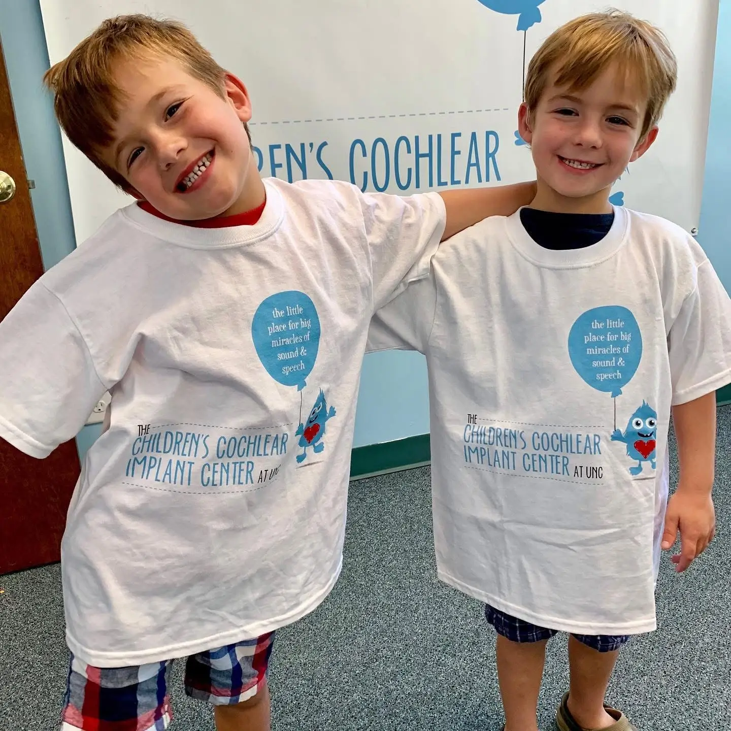 Two smiling children wearing Children’s Cochlear Implant Center at UNC T-shirts, celebrating children's healthcare research made possible with foundation funding to the UNC School of Medicine